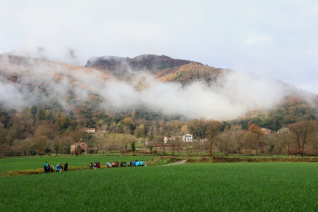 imatge de montanyes envoltades per núvols amb escoltes passant per un camí entre mig